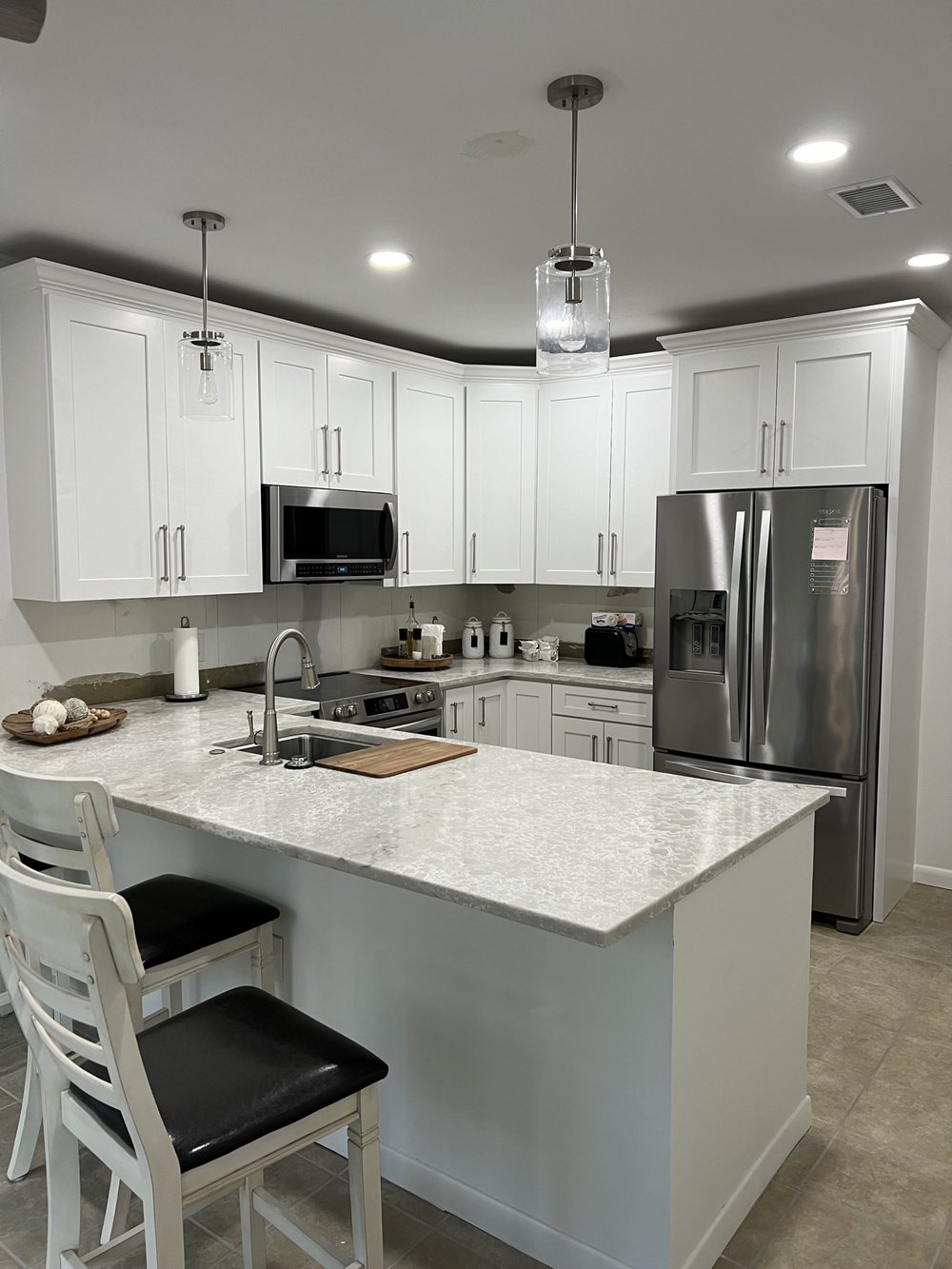 Kitchen remodel by KM Property Maintenance — white shaker cabinets, quartz island, and pendant lighting